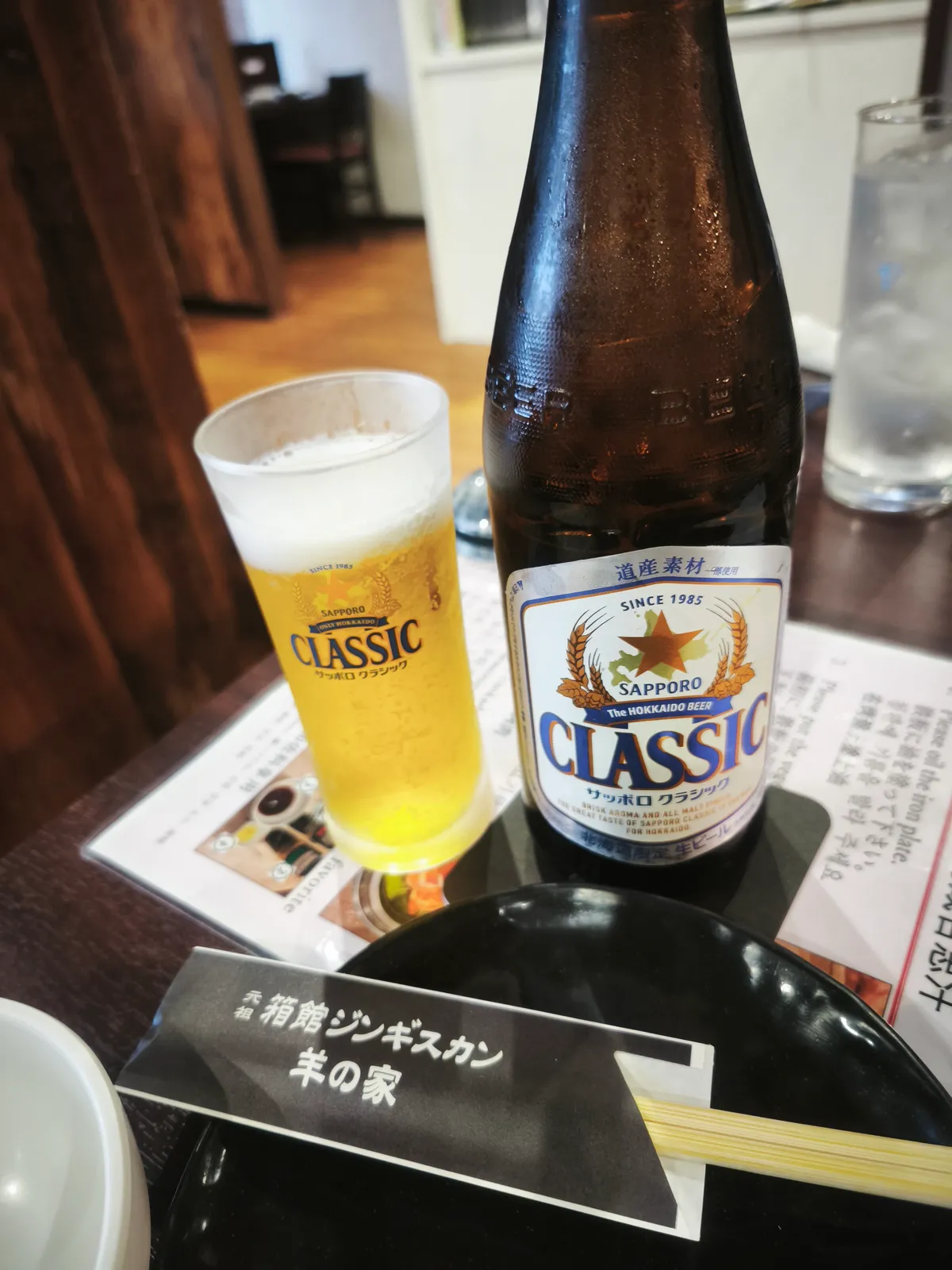 生ビール（サッポロクラシック）のグラスと瓶。テーブルにはお店の名前が入ったカードも置かれている