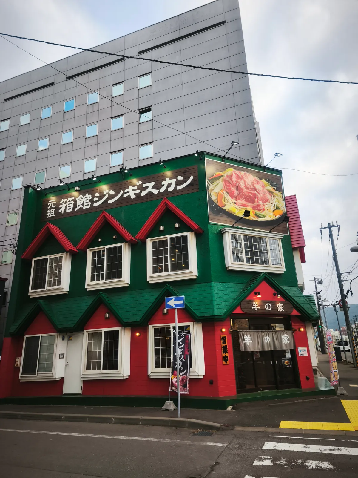 元祖 箱館ジンギスカン 羊の家の外観。緑と赤を基調にした建物に「元祖 箱館ジンギスカン」の看板が掲げられている