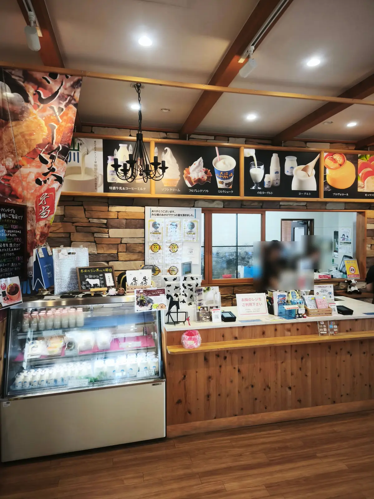山川牧場ミルクプラントの店内カウンター。特濃牛乳やソフトクリームなどのメニュー写真と冷蔵ショーケース