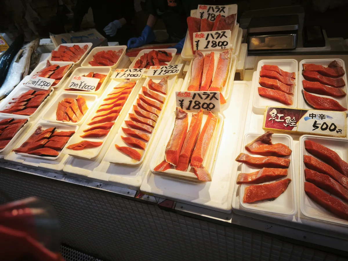 紅鮭やハラスの切り身がトレーに並んだ対面販売の台。手書きの値札がついている
