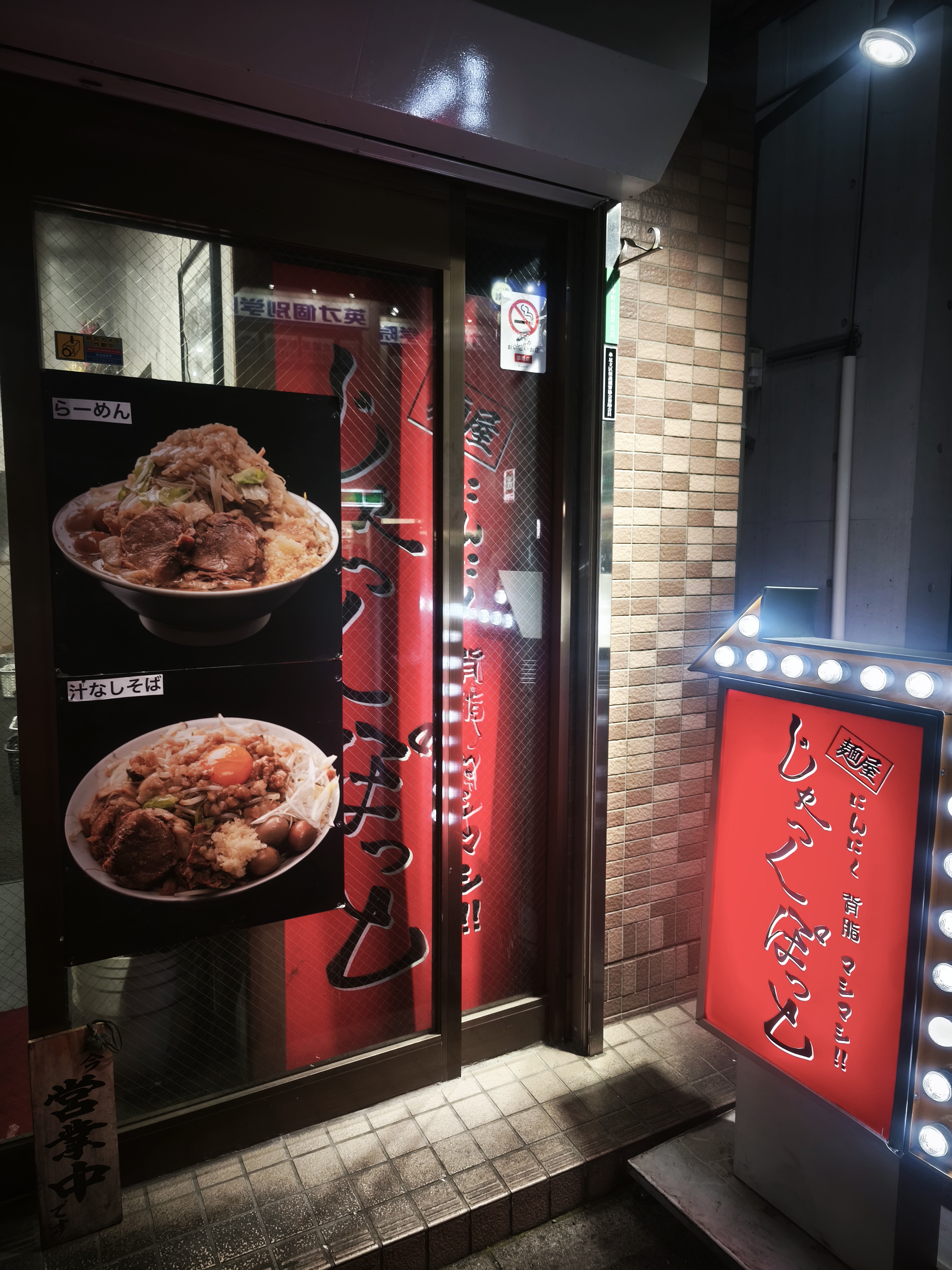 店頭のメニュー写真とドア。らーめんと汁なしそばの写真パネル