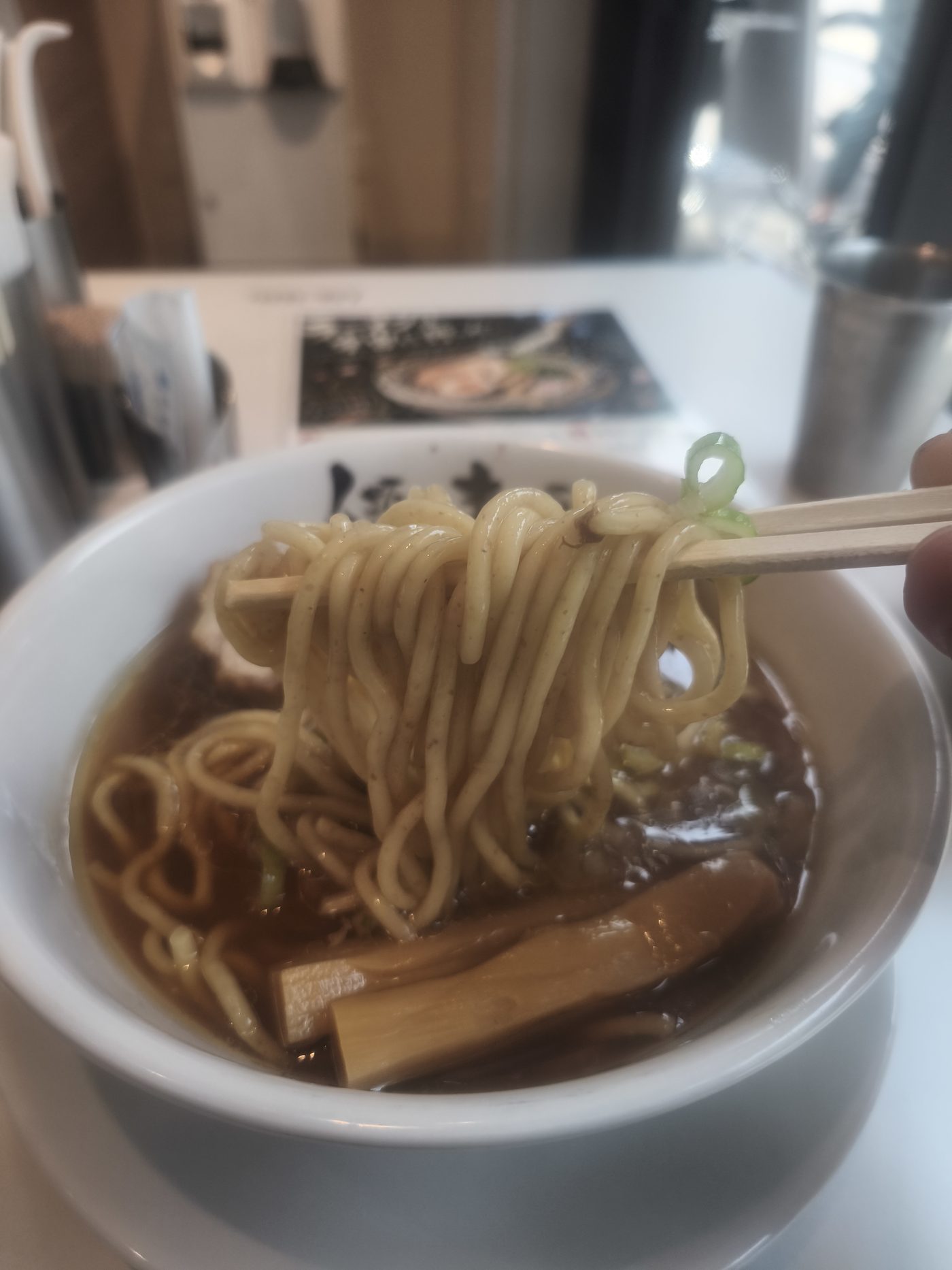 太麺を箸で持ち上げたところ。コシのある中太〜太麺