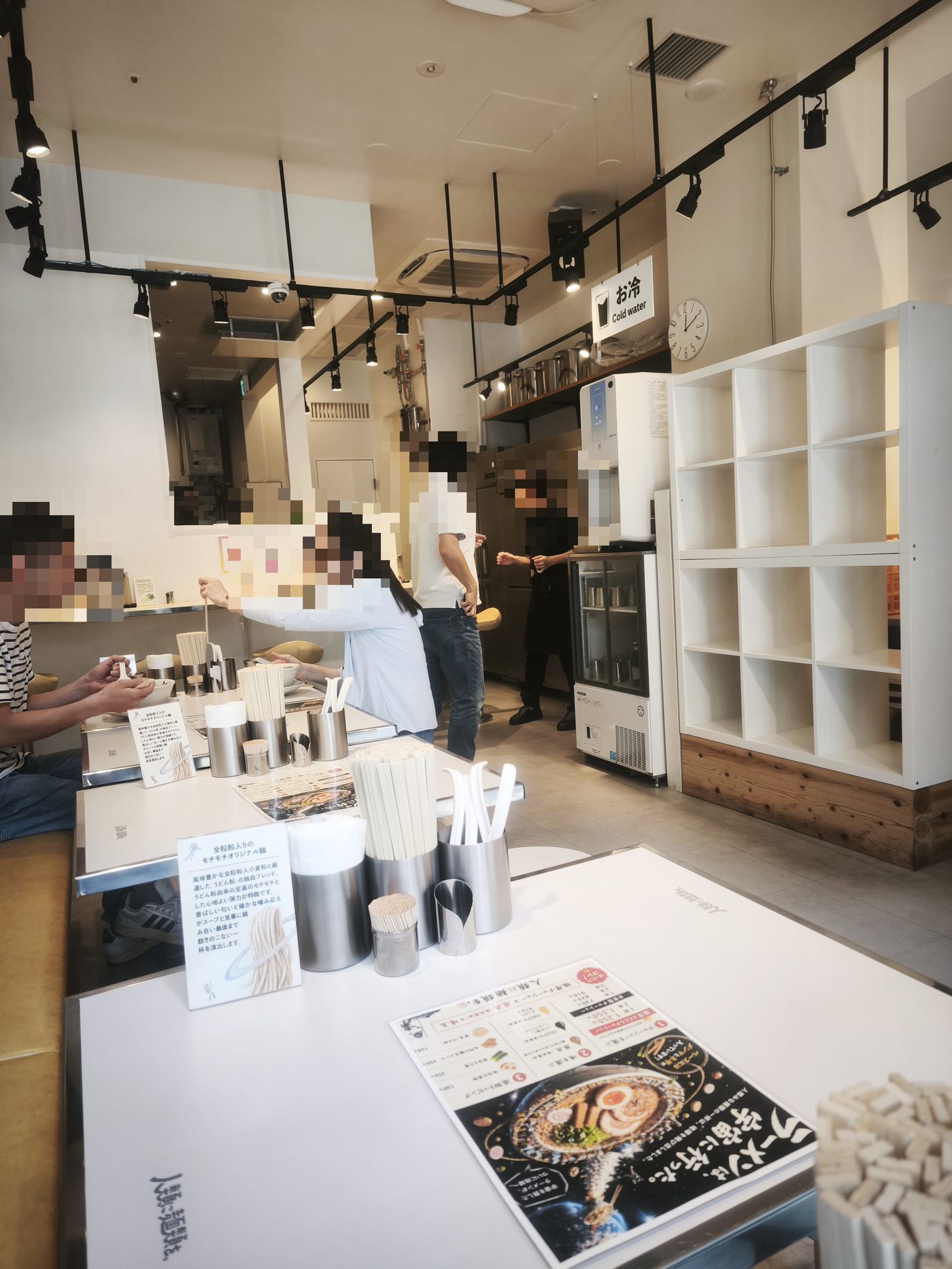 人類みな麺類 埼玉川口店の店内。白を基調にした明るいカウンター席(人物の顔はぼかし処理しています)